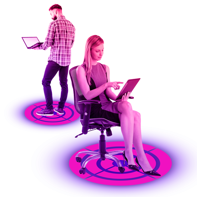 Women looking at an ipad sat on a chair and a man looking at a laptop stood up