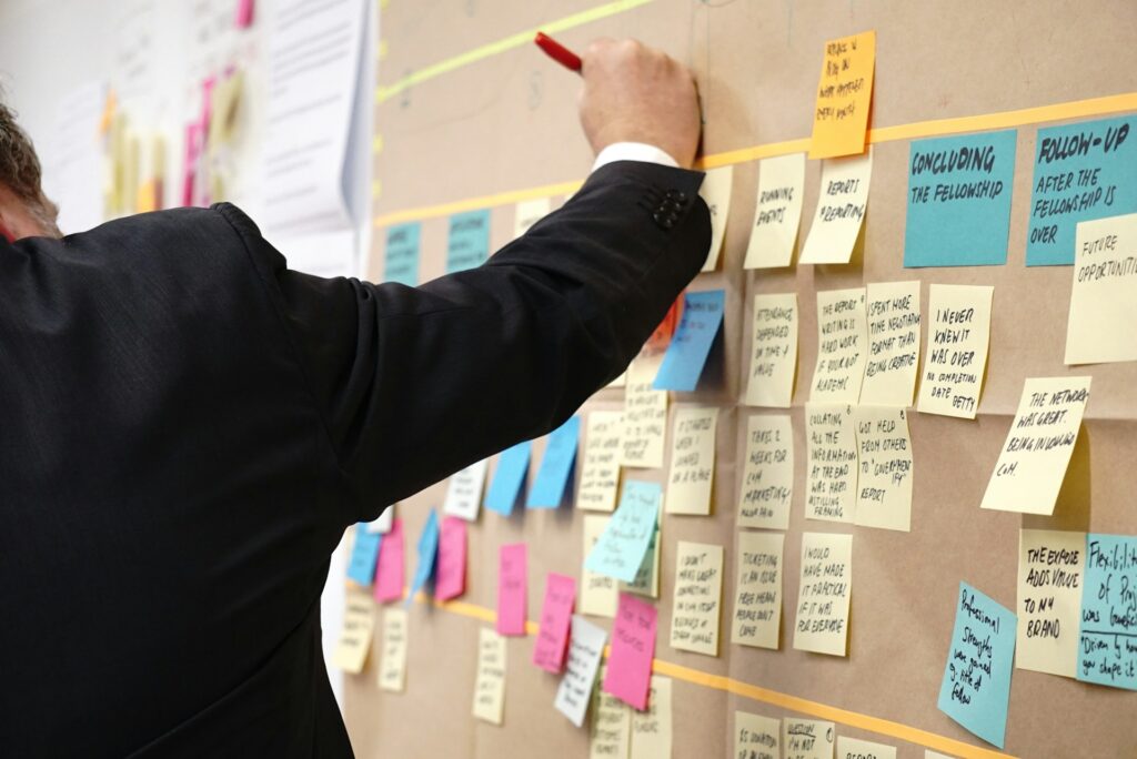 Man writing on post-it notes on a board to make notes about a project.