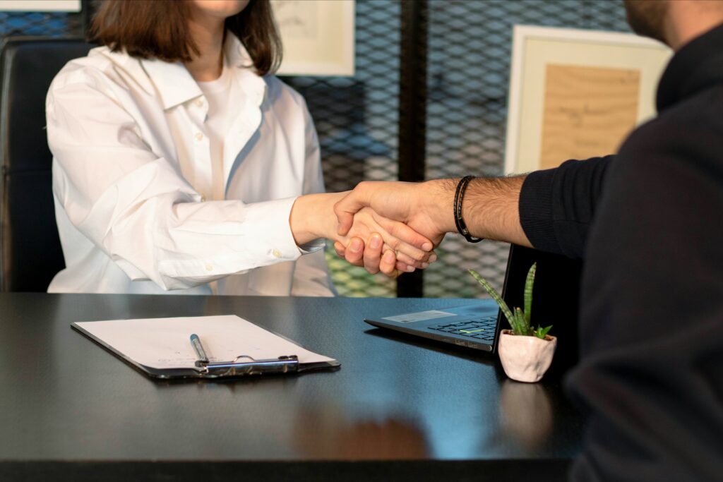 People shaking hands across a table following a job interview.