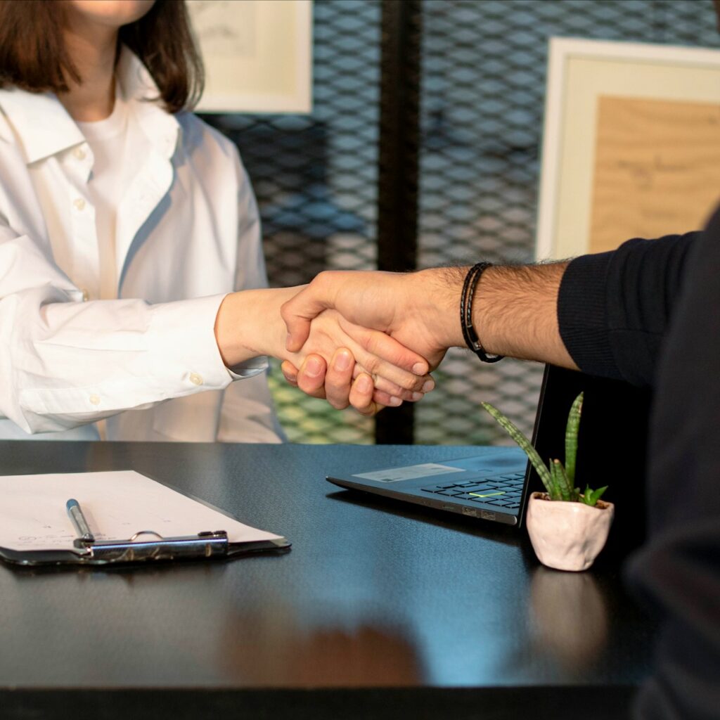 People shaking hands across a table following a job interview.